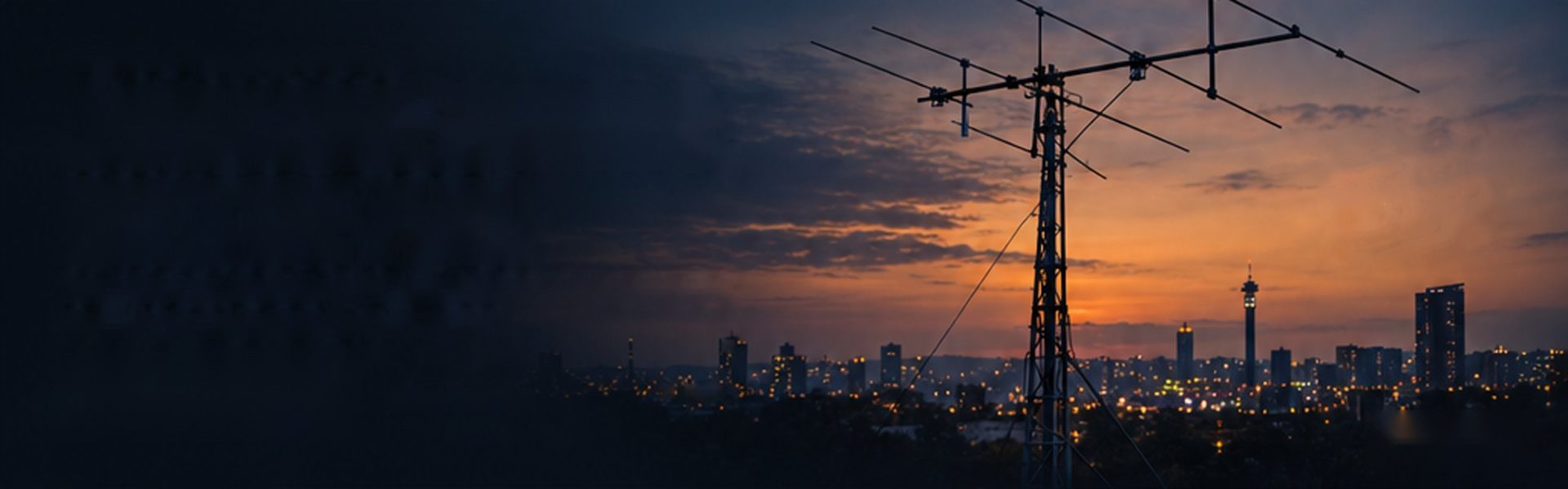 An antenna mast against the Johannesburg skyline at dusk